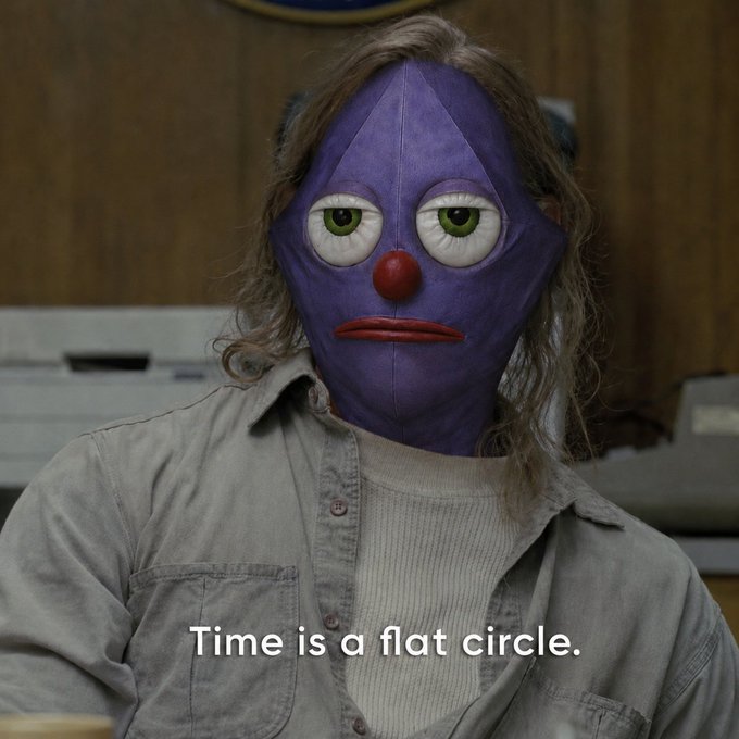 A person wears a purple diamond-shaped clown mask with a red nose and bulging eyes, accompanied by the text 'Time is a flat circle.'