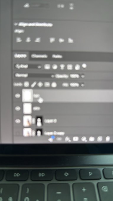 A photograph of a laptop screen displaying Adobe Lightroom or Photoshop, showing the Alignment and Transform panels with layer thumbnails, with the keyboard visible at the bottom.