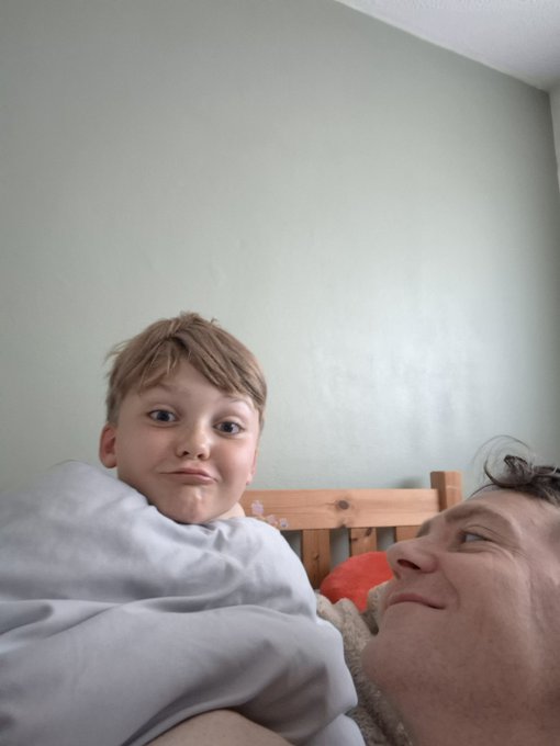 A young boy with a cheeky smile looks down at the camera while being held by his dad, who is gazing up at him adoringly. The tender father-son moment perfectly captures the "Dad and lad Sunday" balance referenced in the post, showing a heartwarming weekend connection before the upcoming birthday celebrations.