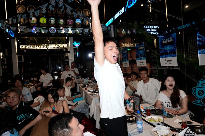 A man triumphantly raises his arm amid cheers at Bitget's Universal Cup viewing party, hosted at Goose Island Brewhouse, where Argentina and Spain fans gathered for a lively evening of football, lucky draws, and celebration.