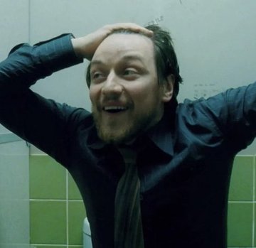 A man with tousled brown hair and a beard, wearing a dark shirt and tie, poses with his hands on his head against a green-tiled wall, making an exaggerated, playful expression. The casual, candid vibe of the shot fits the post's lighthearted request for opinions on a new profile picture (PFP) for @zemoon_xbt.