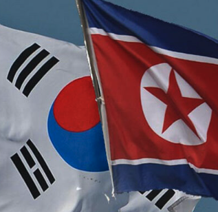 The South Korean flag (Taegukgi) and North Korean flag wave side by side, symbolizing the divided Korean peninsula along the Demilitarized Zone (DMZ) where the recent explosion injured three South Korean military officers during an operation near the Military Demarcation Line.