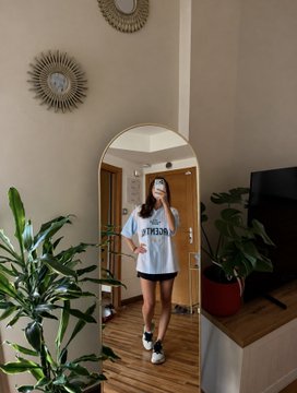 A woman takes a mirror selfie in a casual outfit featuring a white shirt that reads "ARGENTINA," standing in her home with green plants surrounding her, reflecting her support for Argentina in the World Cup final. The image ties to her post about declining a date to focus on predicting the match outcome through OKX's new market feature.