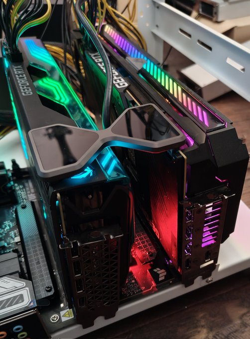 A close-up of a gaming PC interior showcases a GeForce RTX graphics card and RGB-illuminated components glowing in vibrant green, blue, and pink colors.