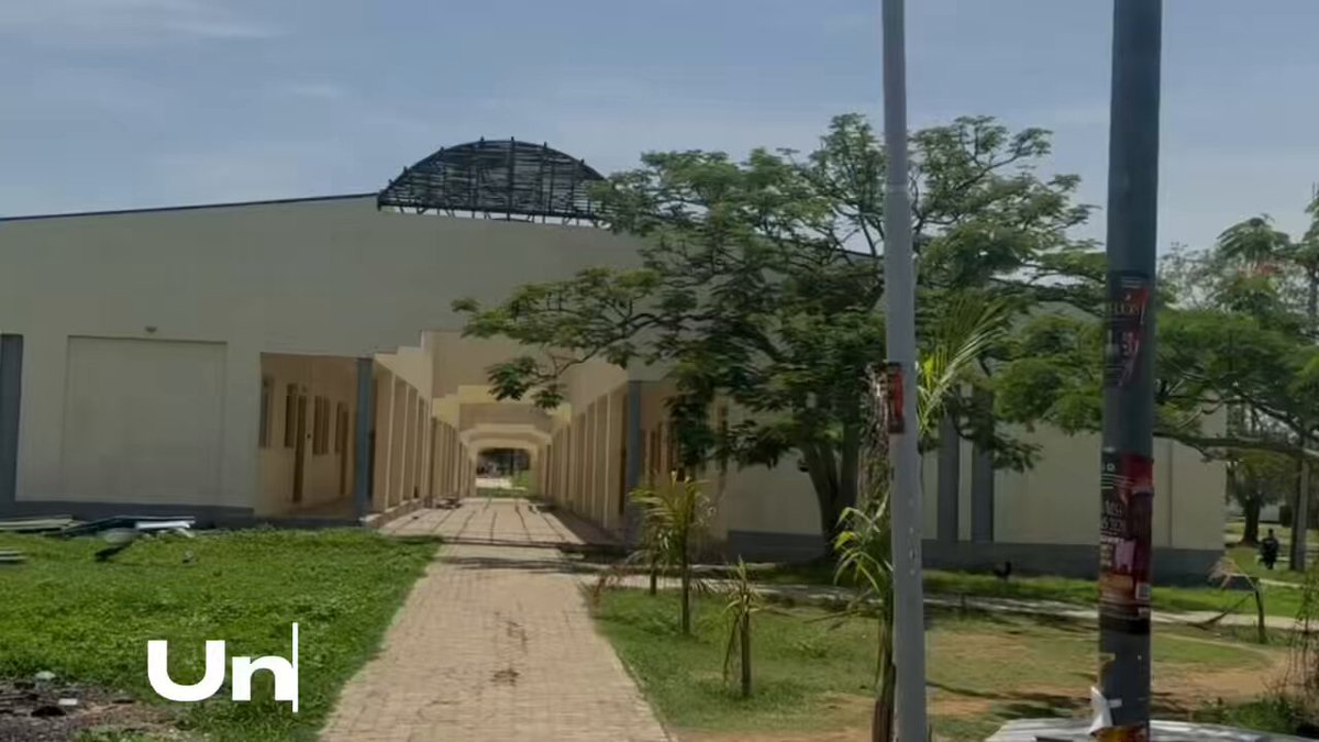 The image shows a large white building with a dome roof, surrounded by trees and bushes. There are two people standing near the building, possibly discussing or admiring its architecture. The photo also contains text that reads "Un" and "PREACHING THE MANTLE GOSPEL gMNT I’m Red, a proud believer @Mantle_Official I hosted a small session at my Uni where I introduced builders in my department to: ... the Mantle Turing Test Hackathon and why I believe it's one of the most exciting opportunities for builders".