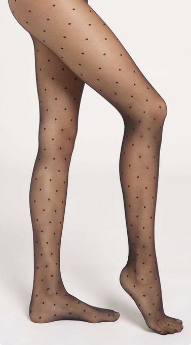 A pair of legs wearing sheer black polka-dot tights against a light background.