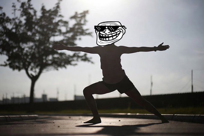 A silhouetted figure performs a warrior yoga pose at sunrise, wearing a "troll face" meme mask instead of a head, capturing the absurd early-morning energy of a crypto troll getting ready to cause mischief on a Saturday. The image playfully reinforces the post's joke about "trolls" already in action while others sleep, with the meme mask serving as the perfect visual representation of internet trolling culture.