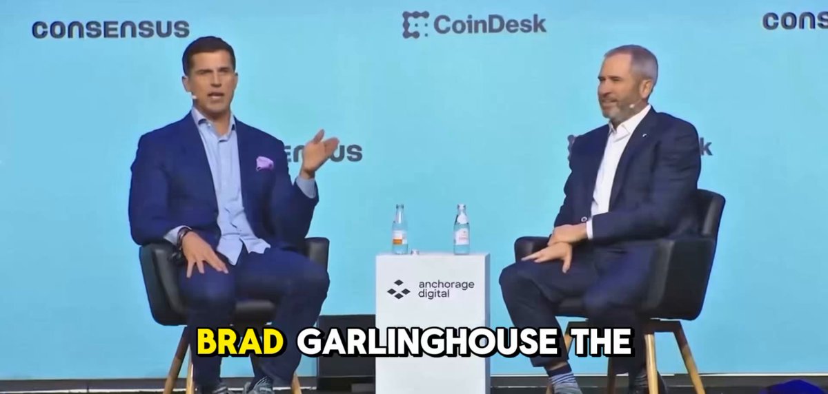 The image features two men sitting across from each other at a round table, engaged in conversation with an audience behind them. Both individuals are wearing suits and ties, indicating a formal or professional setting for their discussion. The background includes text that reads "consensus", "Coinsk", "Ripple", and "3 TRILLION INCOME".

The two men appear to be discussing the future of the coin industry. One man is sitting on the left side of the table, while his counterpart is seated closer to the right side. They seem to be sharing their insights about cryptocurrency markets, with one man emphasizing the importance of clarity and organization in such a rapidly growing space. The event could potentially lead to substantial financial gains if executed correctly.
