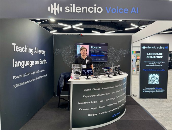 A booth for 'silencio Voice AI' at a conference, featuring the tagline 'Teaching AI every language on Earth' and a 'LANGUAGE CHALLENGE' banner with a QR code.
