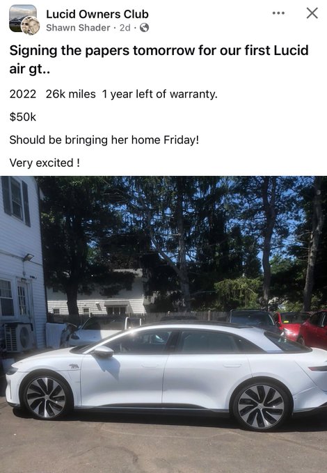 A Facebook post from "Lucid Owners Club" by Shawn Shader announces the purchase of a 2022 Lucid Air GT for $50k with 26k miles and one year of warranty remaining, paired with a photo of the white Lucid Air sedan parked outside a house—aligning with the celebratory $LCID congratulations message.