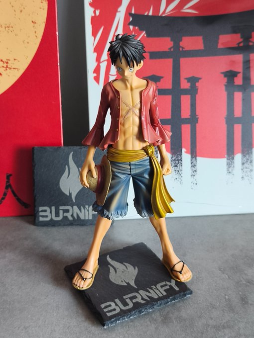 A figurine of Monkey D. Luffy from the anime One Piece, showing him in his iconic red vest, yellow sash, and blue shorts, standing on a black base labeled 'BURNIFY'.