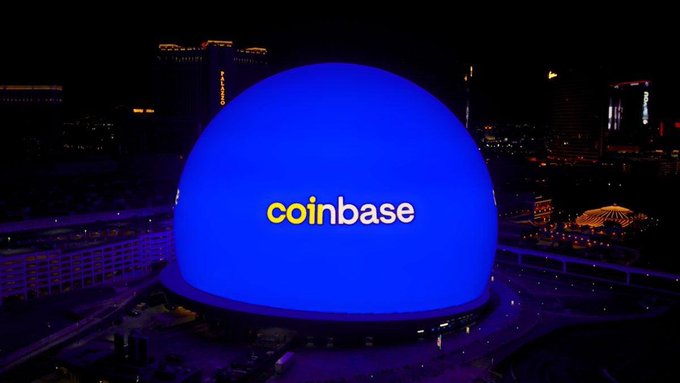 The image features a large blue dome that has "Coinbase" written on it. This dome appears to be located in Las Vegas, Nevada, as indicated by the city skyline visible in the background. The main focus of the image is the base itself, which is a product developed by Coinbase and used for connecting wallets with DeFi apps directly to AI assistants like OpenAI's ChatGPT or Claude. This innovative tool allows users to interact with crypto applications through normal chat prompts instead of using traditional methods such as signing in via email or filling out forms.