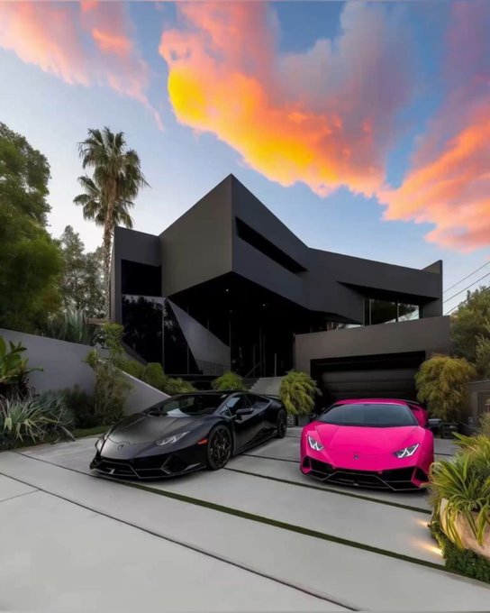 Two Lamborghini Huracáns—one matte black and one hot pink—are parked in the driveway of a modern angular black house at sunset with palm trees framing the scene.