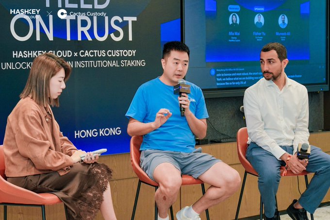 Three panelists seated on a stage at a 'HASHKEY CLOUD x CACTUS CUSTODY' event in Hong Kong, with the backdrop reading 'BUILT ON TRUST' and 'UNLOCKING INSTITUTIONAL STAKING'.