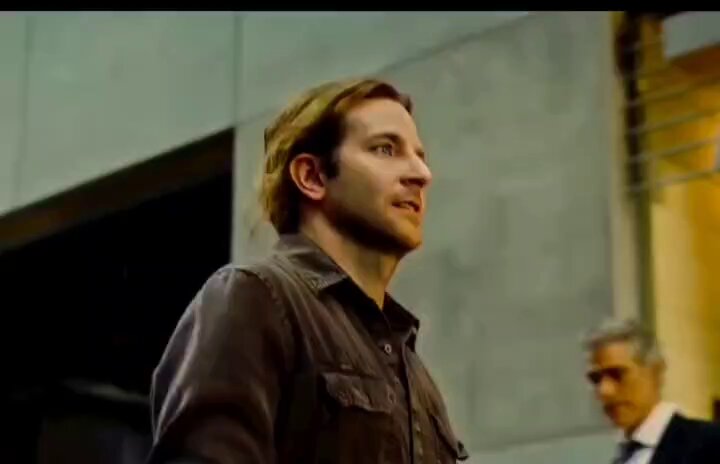 The image shows a man wearing a brown jacket standing next to another person, who appears to be a businessman dressed in a suit. The background of the scene includes a building with a window and a door. In the corner of the frame, there is text that reads "When people ask you how you got rich but what you do is illegal so you just say bitcoin". This suggests that the man wearing the brown jacket might be discussing or promoting Bitcoin as an alternative to traditional wealth accumulation methods.