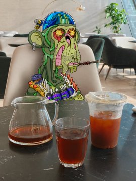 The image features a cartoon monkey sitting at a table with two cups of coffee, one being closer to the viewer while the other is further away. The scene takes place in an indoor setting, possibly a cafe or restaurant. A caption below the image reads "GM APE FAM 今天的你喝咖啡了吗 期待收货 @Mountain_ville 的咖啡性价比很高 340克只要20美元/138元人民币 品质也在线 非商业豆".