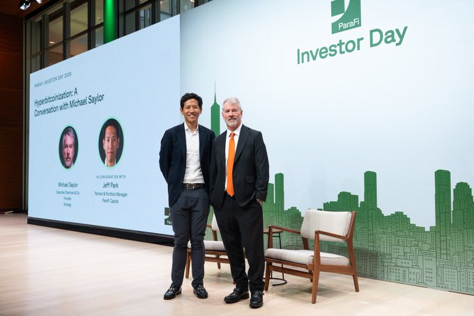 Two men pose on stage at ParaFi Investor Day 2024, with the backdrop indicating a "Hyperbitcoinization: A Conversation with Michael Saylor" session featuring Jeff Park of ParaFi Capital, preceding a fireside chat with the MicroStrategy founder. The image aligns with the post by capturing the presenters just before their discussion on hyperbitcoinization and founder advice in the age of superintelligence.