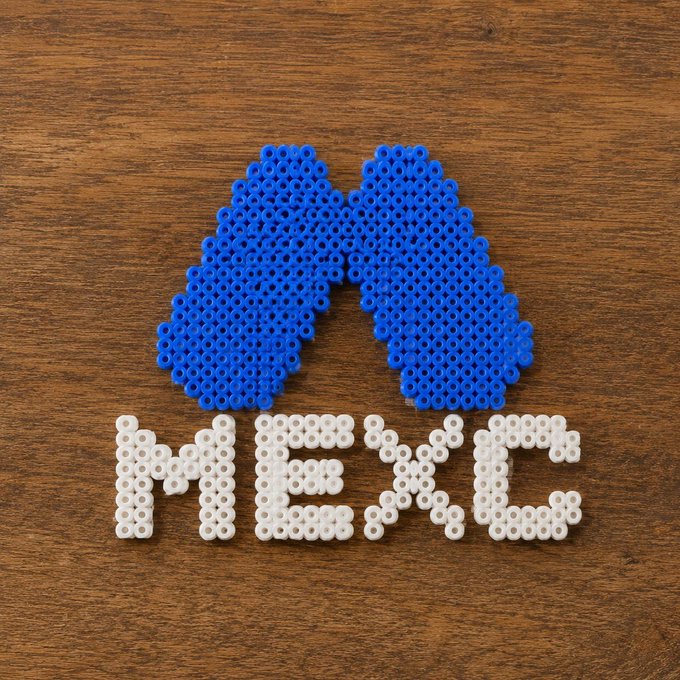 A craft arrangement of blue and white fuse beads on a wooden surface spelling out 'MESIC'.