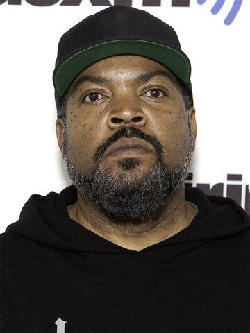 A close-up photo of a bearded man wearing a black hoodie and a black baseball cap with a green brim.