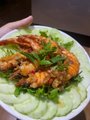 The image shows a plate of food with shrimp, lettuce, and cucumbers arranged on top of a white plate. The dish appears to be a healthy meal option, possibly featuring a salad or a seafood dish. The background seems to be blurred, but there is a person's hand visible in the scene. The post includes text that reads "Thử thách 1h sáng ngủ 4h sáng dậy sớm để xuống biển đó bình minh và cái kết."