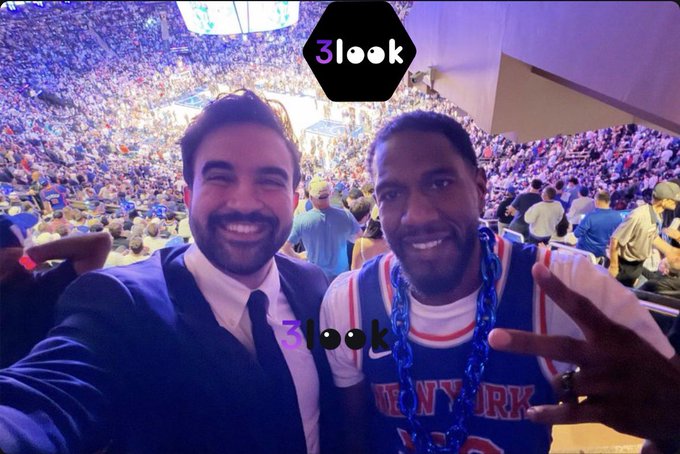 The image features two men posing together at a basketball game with their arms around each other's shoulders. They are both wearing jerseys that say "New York", indicating they might be fans of the New York City basketball team. The background shows a crowd of people watching the game, and there is a banner in the scene that reads "3look". This suggests that the image was taken at a sports event where the men decided to take a photo together for their followers on social media platforms like Instagram or Twitter.