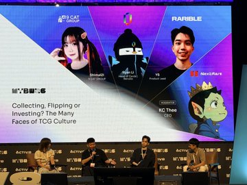 A panel discussion at a conference with four people seated on stage in front of a large screen displaying 'MY/BU:6' and 'Collecting, Flipping or Investing? The Many Faces of TCG Culture', along with various avatars and logos.