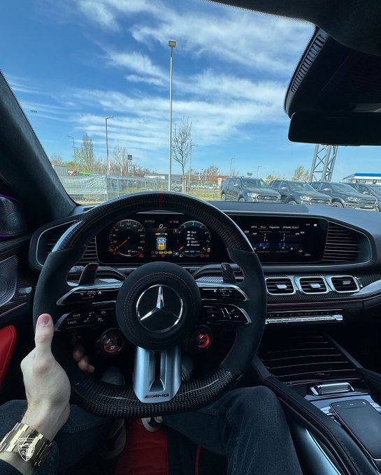 A driver's hand grips the steering wheel of a Mercedes-AMG, with the dashboard display visible and a row of cars parked outside under a bright blue sky.

The image perfectly complements the post's optimistic, "new beginnings" energy — a luxury Mercedes-AMG cockpit paired with the hopeful message of a profitable new month ahead, while tagging @River4fun and $RIVER to signal bullish sentiment for the crypto community.