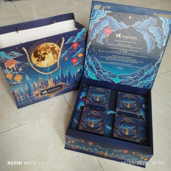 A Mid-Autumn Festival themed gift set from VT Markets featuring a decorative blue bag with moon and lantern designs, and an open box containing individually packaged mooncakes with traditional Vietnamese and English text, photographed on 15/09/2026.