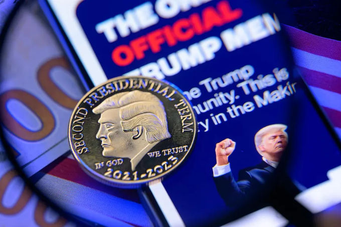 A commemorative gold coin labeled "Second Presidential Term, In God We Trust, 2021-2025" featuring Donald Trump's profile rests atop promotional materials for "The Official Trump Meme" coin, visually symbolizing the $3.8 billion losses reported among roughly 1 million investors in the $TRUMP meme coin.