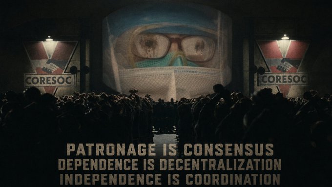 A dystopian scene with a large projected face wearing goggles and a mask on a screen, flanked by banners reading 'CORESOC,' with text stating 'PATRONAGE IS CONSENSUS, DEPENDENCE IS DECENTRALIZATION, INDEPENDENCE IS COORDINATION.'