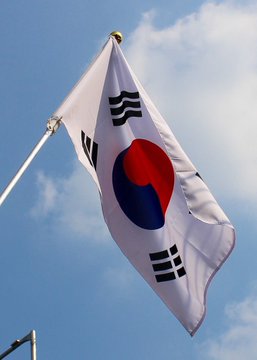 The South Korean flag waves against a blue sky, symbolizing the nation's regulatory actions as it investigates 30 crypto market manipulation cases under new cryptocurrency law.
