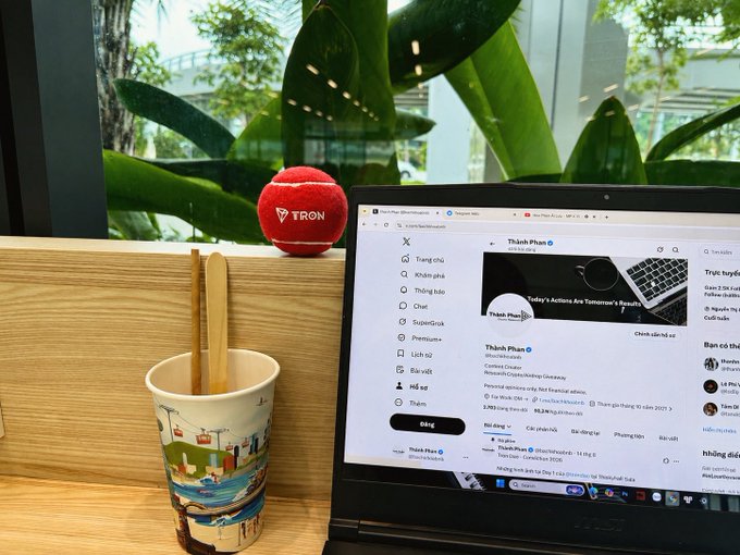 A desk setup featuring a red TRON microphone, a wooden stand holding chopsticks and a ceramic cup, and an MSI laptop displaying a Twitter/X profile for 'Thánh Phan'.