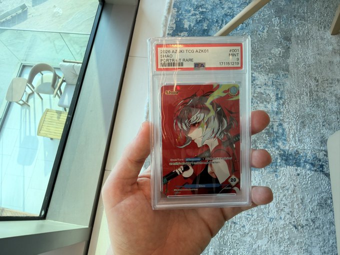 A hand holds a PSA-graded mint 9 trading card featuring the character Shao from AZKi TCG AZK01 Portret Rare, dated 171151219.