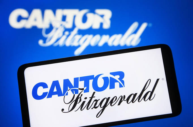 A smartphone displays the Cantor Fitzgerald logo in front of a blue background featuring the same branding, illustrating the firm's optimistic outlook on Bitcoin's market cycle and its potential bottom in the coming months.