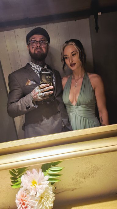 A man in a gray suit with patterned tie and a woman in a green halter dress pose together for a mirror selfie at what appears to be a wedding venue, with the groom showing off his ring.

The image captures the newlyweds celebrating after their wedding weekend, tying in with the post about returning to work after the festivities.