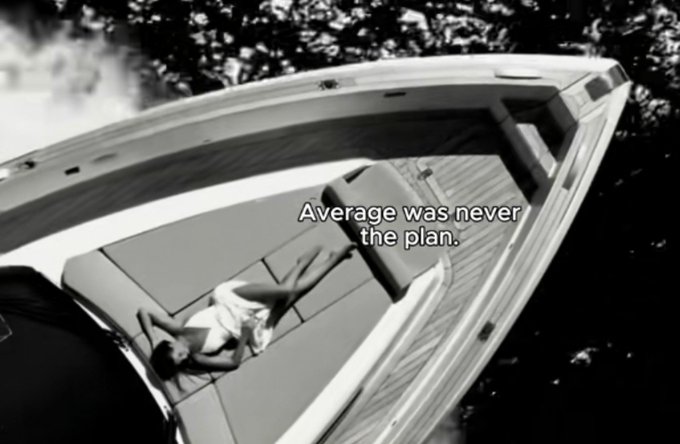 A black and white image shows a woman in a white dress lying on the deck of a luxury yacht, with the text 'Average was never the plan.'