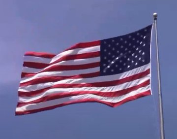 An American flag waving in the wind against a clear blue sky.