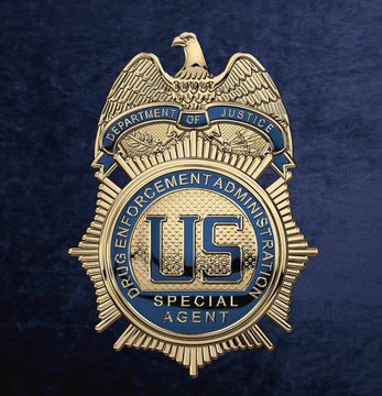 A gold and blue badge featuring an eagle at the top reads 'DEPARTMENT OF JUSTICE' and 'DRUG ENFORCEMENT ADMINISTRATION' around a central 'US' emblem, with 'SPECIAL AGENT' inscribed below.