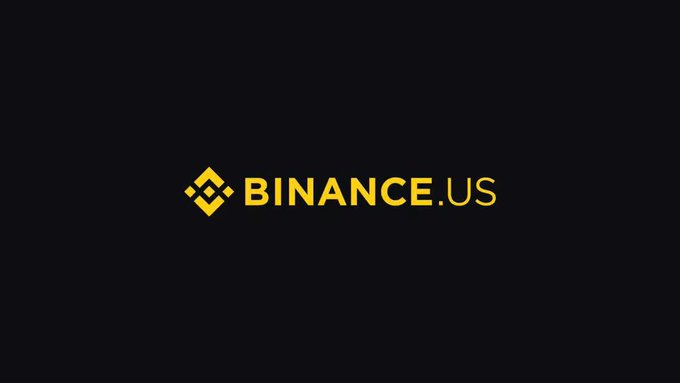 The image displays the Binance.US logo in yellow text on a black background, representing the cryptocurrency exchange platform mentioned in the article about its efforts to raise $100 million at a valuation of $1 billion.