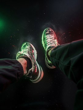 The image shows a pair of feet wearing camouflage sneakers, with their toes pointing towards the top left corner of the frame. The background appears to be black, but there are some sparks coming from the right side, adding an element of visual interest to the scene. The caption "BAPE × BAYC Landed Wearing @BoredApeYC feels so good. Grail #5 Secured" is written below the image, which seems to be a reference or description related to the sneakers and their wearer's experience.
