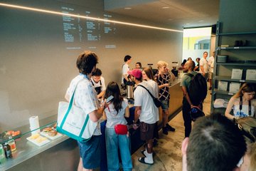 A diverse crowd of attendees gathers at what appears to be a tech conference booth, examining displays and informational materials projected on a wall, illustrating the grassroots interest in WalletConnect's user-friendly blockchain technology. The image captures the engaged community engagement that demonstrates real-world adoption of decentralized Web3 infrastructure.