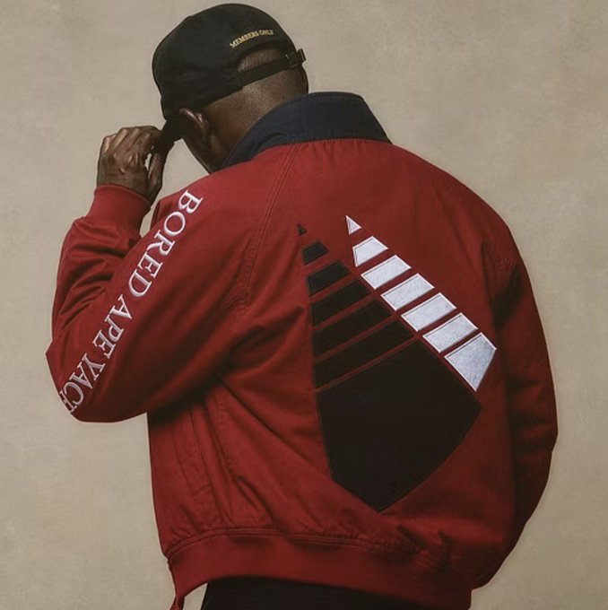 A man wearing a black 'MEMBERS ONLY' cap is photographed from behind in a red bomber jacket featuring 'BORED APE YAC' text on the sleeve and a diamond graphic on the back.