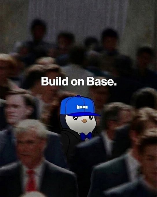 The image features a cartoon penguin wearing a blue hat, standing out among a group of people dressed in suits. The text "Build on Base" is written above the penguin's head, indicating that they are part of an event or gathering related to construction or building projects. The crowd consists of various individuals, some of whom appear to be wearing ties, suggesting a formal or professional setting for this event.