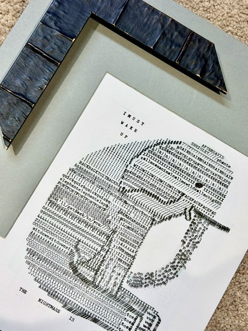 A framed print featuring an elephant created entirely from typewriter characters, with the text 'I MUST WAKE UP' and 'THE NIGHTMARE IS' visible.