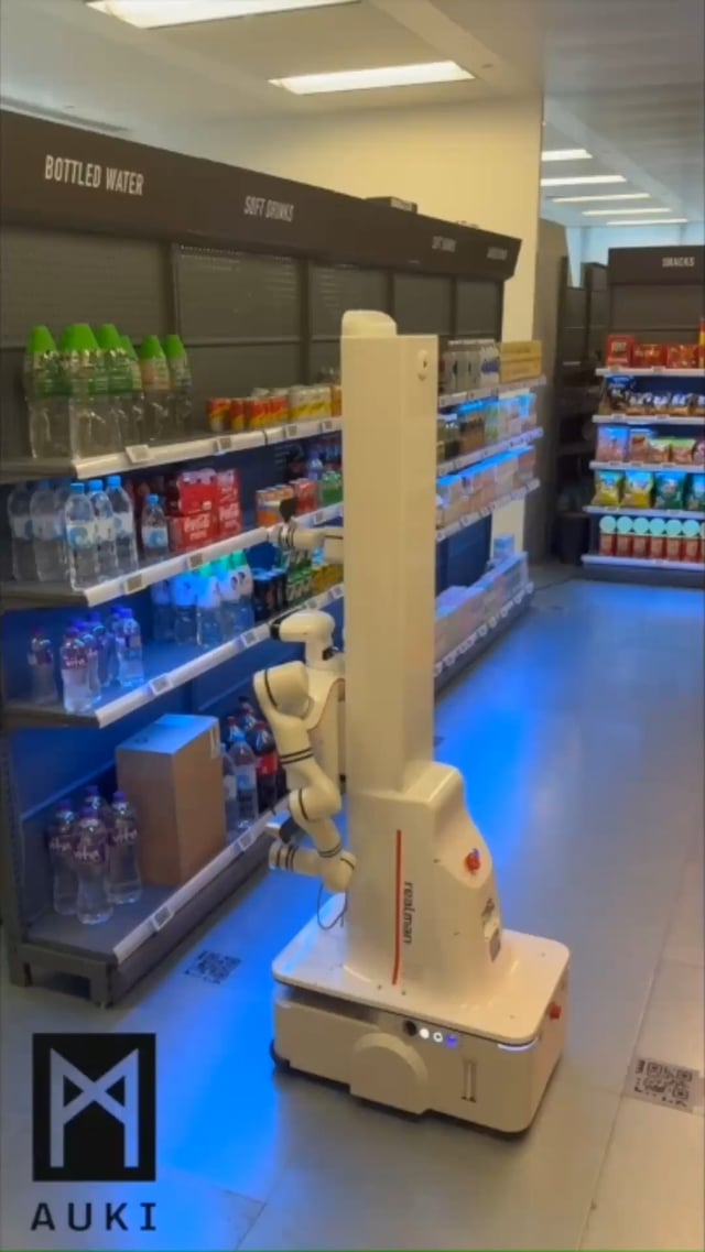 The image features a white robot with blue lights, likely designed for use in a grocery store setting. The robot appears to be walking down an aisle filled with various items such as bottles of water displayed on shelves. The robot's purpose seems to be to assist customers and manage inventory within the store. The post suggests that this robot could potentially be used by retailers to train their robots, which would allow them to learn how to efficiently navigate a grocery store environment and perform tasks like restocking shelves or assisting customers with finding products.