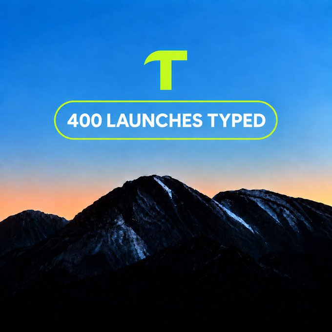 A graphic with a mountain landscape at sunset featuring a large yellow 'T' logo and text reading '400 LAUNCHES TYPED' inside a yellow outlined pill shape.