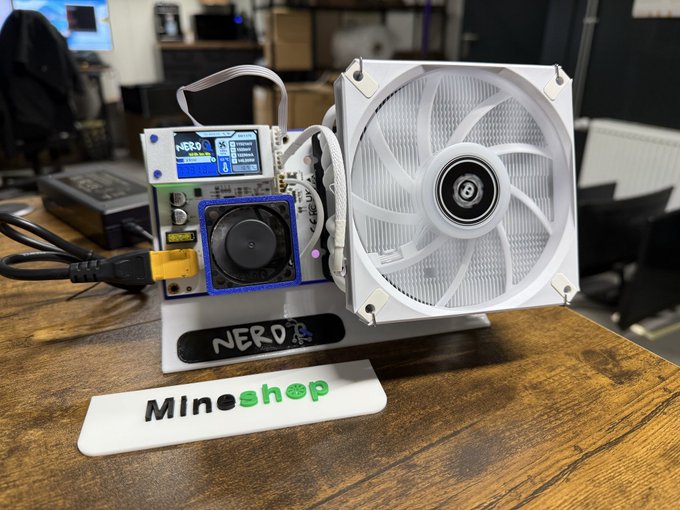 The image shows a compact home mining device branded "NERO" with "Mineshop" displayed on the desk mat, featuring a large white cooling fan alongside the exposed circuit board and display screen of the NerdQX miner. This setup visually reinforces the post's description of the NerdQX as a quiet, plug-and-play home mining rig using BM1370 ASIC chips.