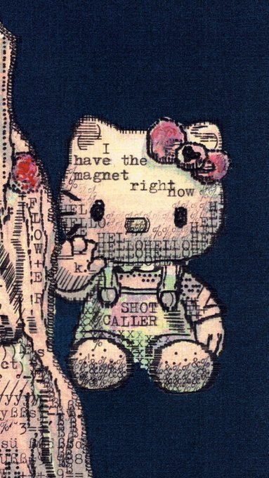 A Hello Kitty-themed mixed media collage figure on a dark blue fabric background, featuring the text "I have the magnet right now" across its face and "SHOT CALLER" on its overalls. The artwork complements the "$kitty" ticker reference, showcasing a creative, street-art style interpretation of the iconic character.
