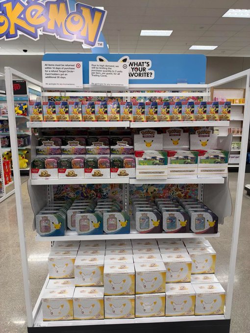 A retail store display prominently features a large Pokémon sign above shelves stocked with Pokémon trading card game products, including tins, booster bundles, and blister packs priced at $40. The "What's Your Favorite?" header and "Booster Bundle galore" caption tie together the abundant collection of Pokémon TCG merchandise available for purchase.