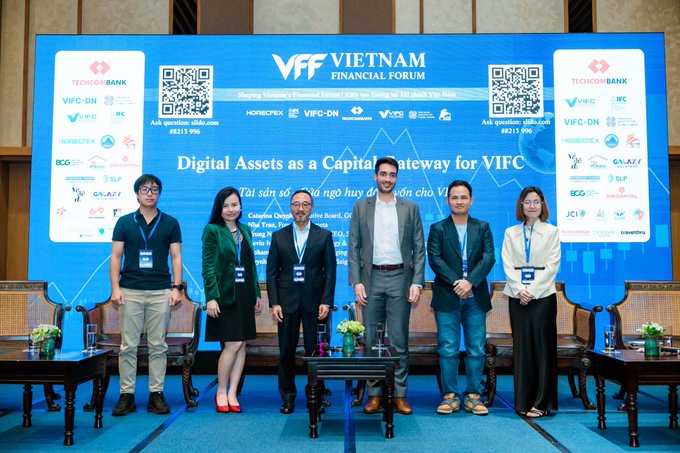 The image shows six professionals posing in front of a "VFF Vietnam Financial Forum" backdrop with the theme "Digital Assets as a Capital Gateway for VIFC," featuring sponsors like Techcombank, IFC, VIFC-DN, and VSD, along with QR codes and a forum date referencing Da Nang in 2026. The scene captures the international forum mentioned in the post, where the Newton Foundation representative joined global delegates to discuss how digital assets and tokenized securities can channel institutional capital into Vietnam's emerging international financial centre.